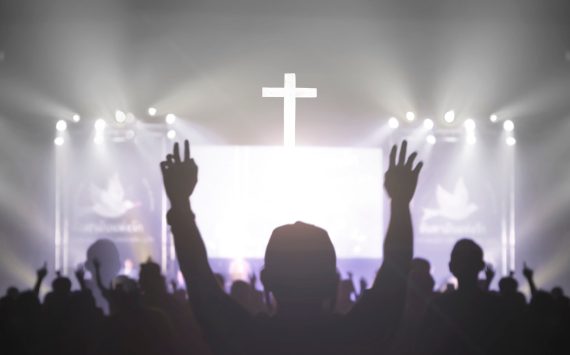 Church worship concept: Christian worship with raised hand at the at the cross cross background